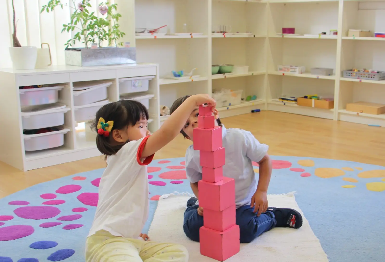Kinder bauen den rosa Turm in einer englischsprachigen Montessori-Kita bei Frankfurt